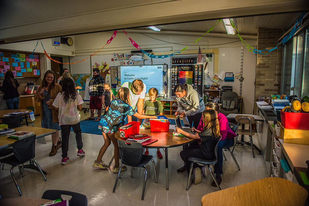 A classroom with students and adults gathered around a table.
