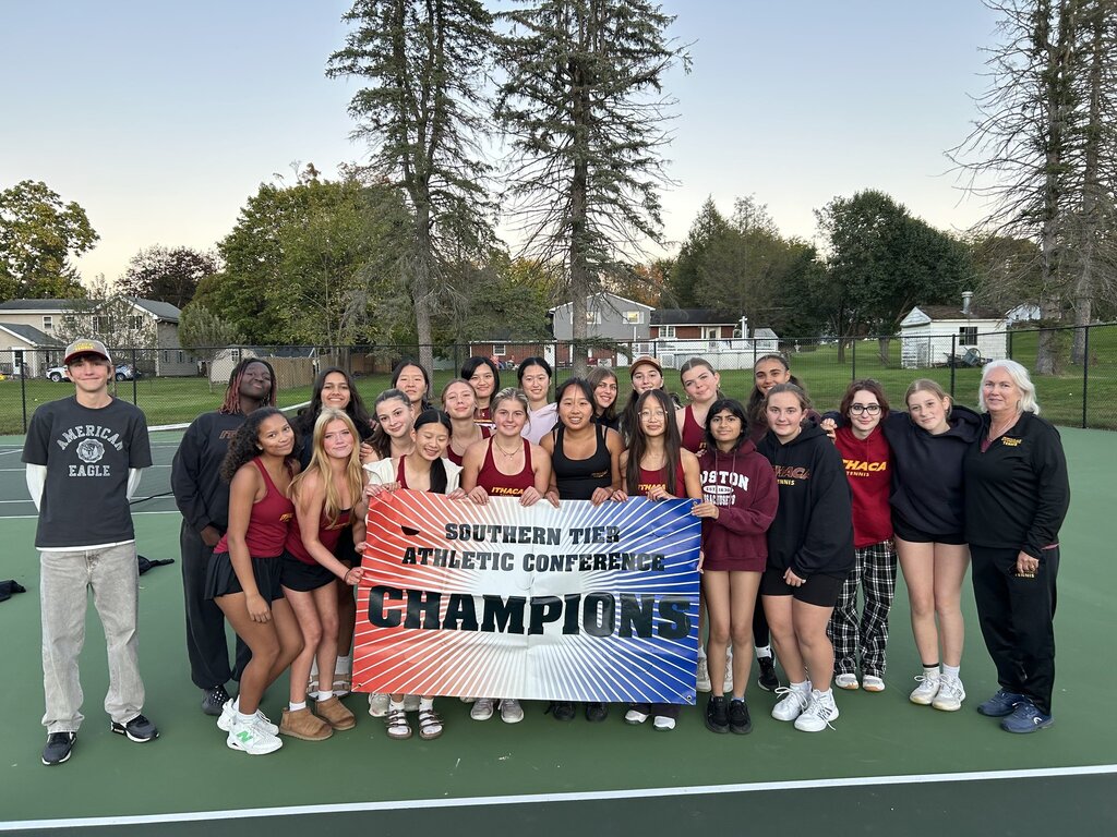 A group of people on a tennis court with a sign that reads "Southern Tier Athletic Conference Champions".