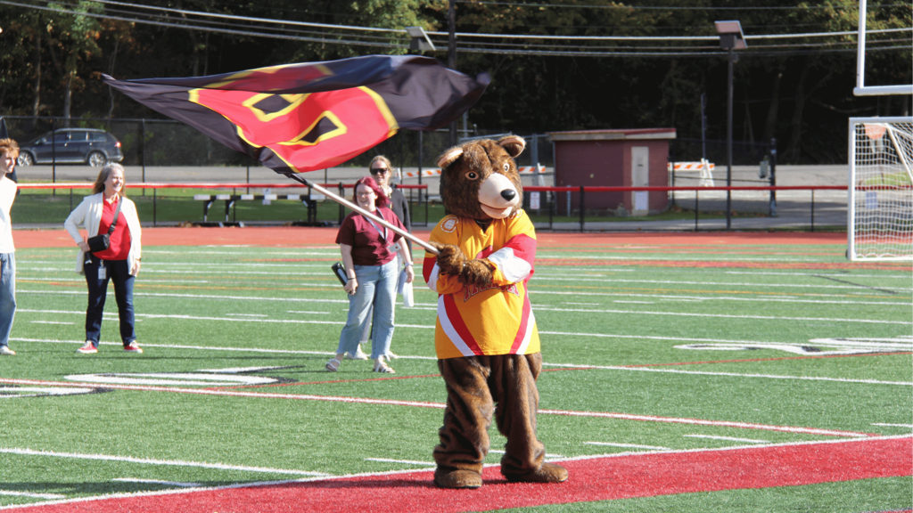 A mascot waving a flag on a football field.