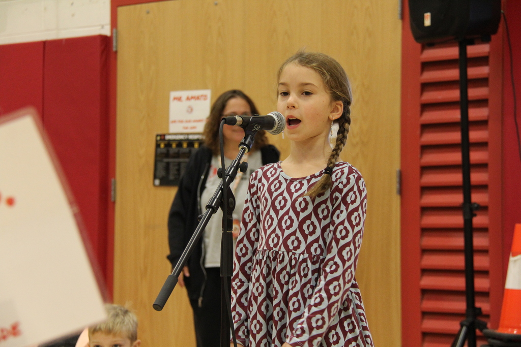 A young girl speaks into a microphone. 