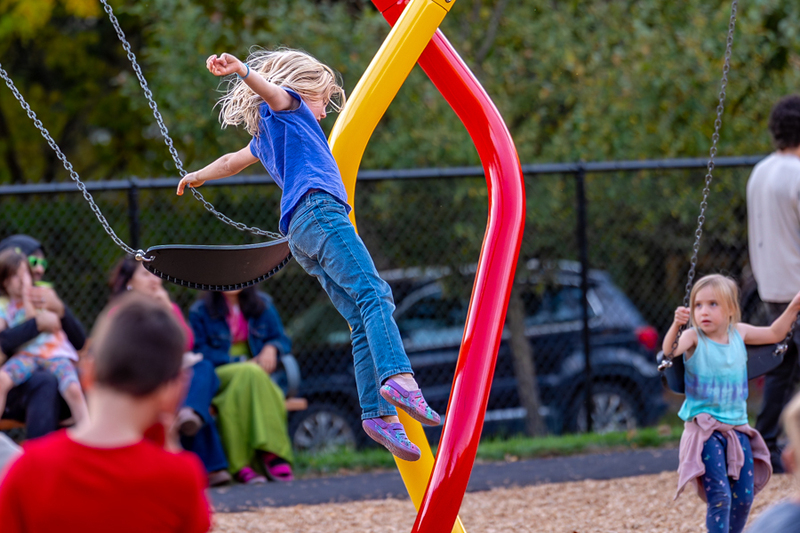 A student jumps off the swing set