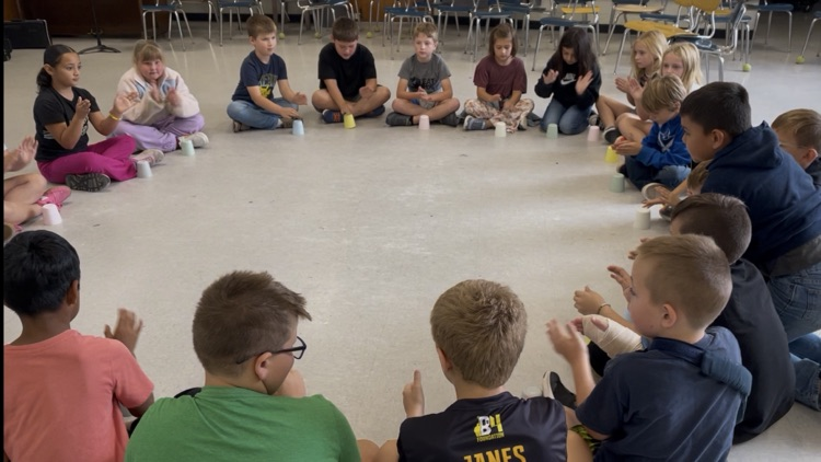 Students sitting in a circle with cups.