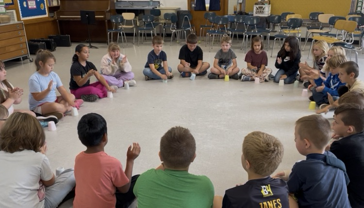 Students sitting in a circle with cups.
