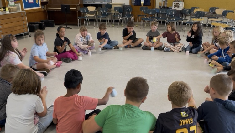 Students sitting in a circle with cups.