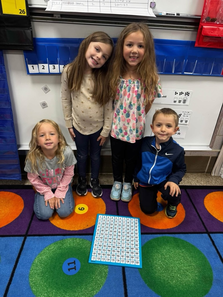 students smiling and sitting on a rug with a puzzle