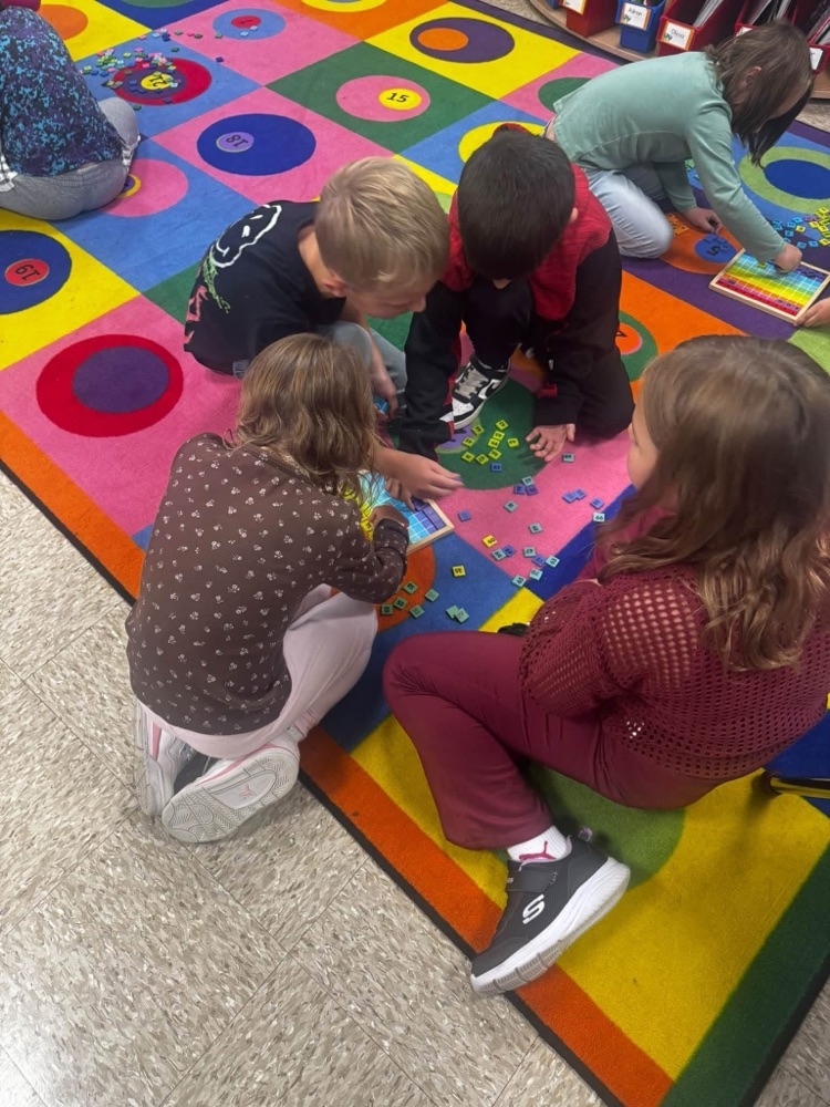 students working together on the rug to solve a puzzle