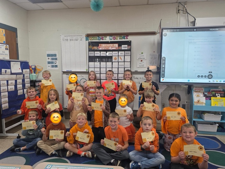 Students sitting on the carpet with awards.
