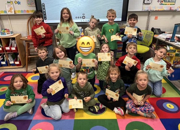 Students sitting on the carpet with awards.