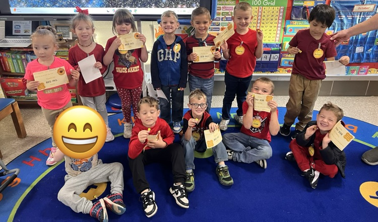 Students sitting on the carpet with awards.