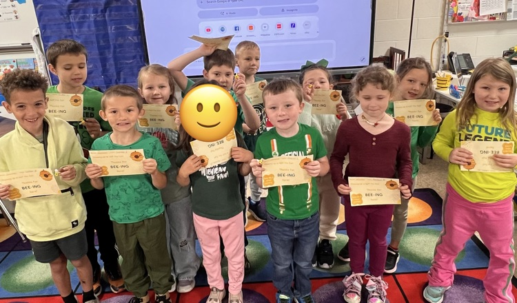 Students standing on the carpet with awards.