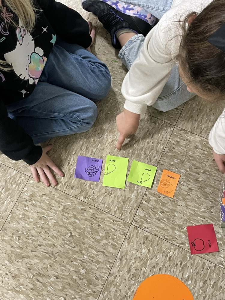 students pointing at pictures of fruit.