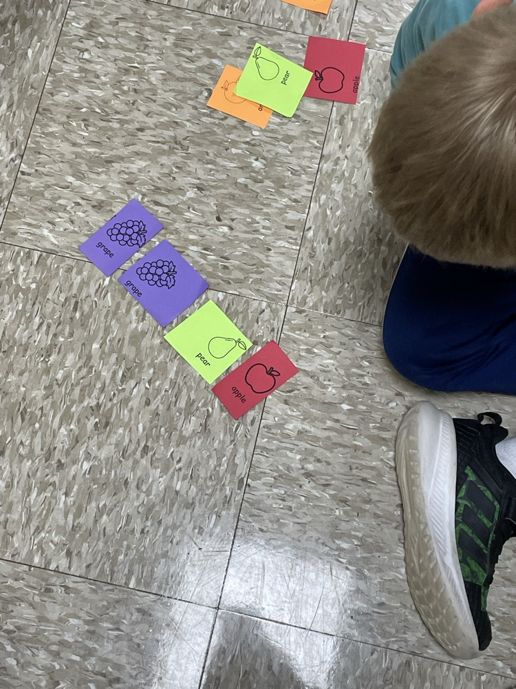 students pointing at pictures of fruit.