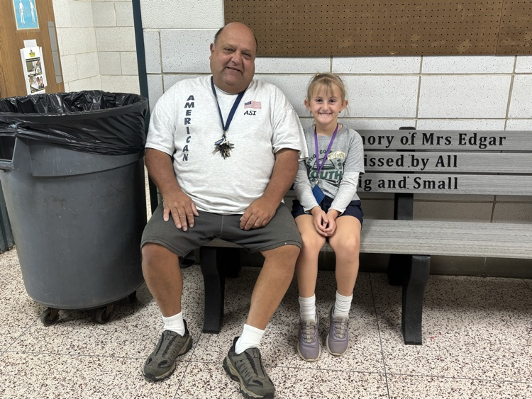 student and staff member sitting together on a bench.
