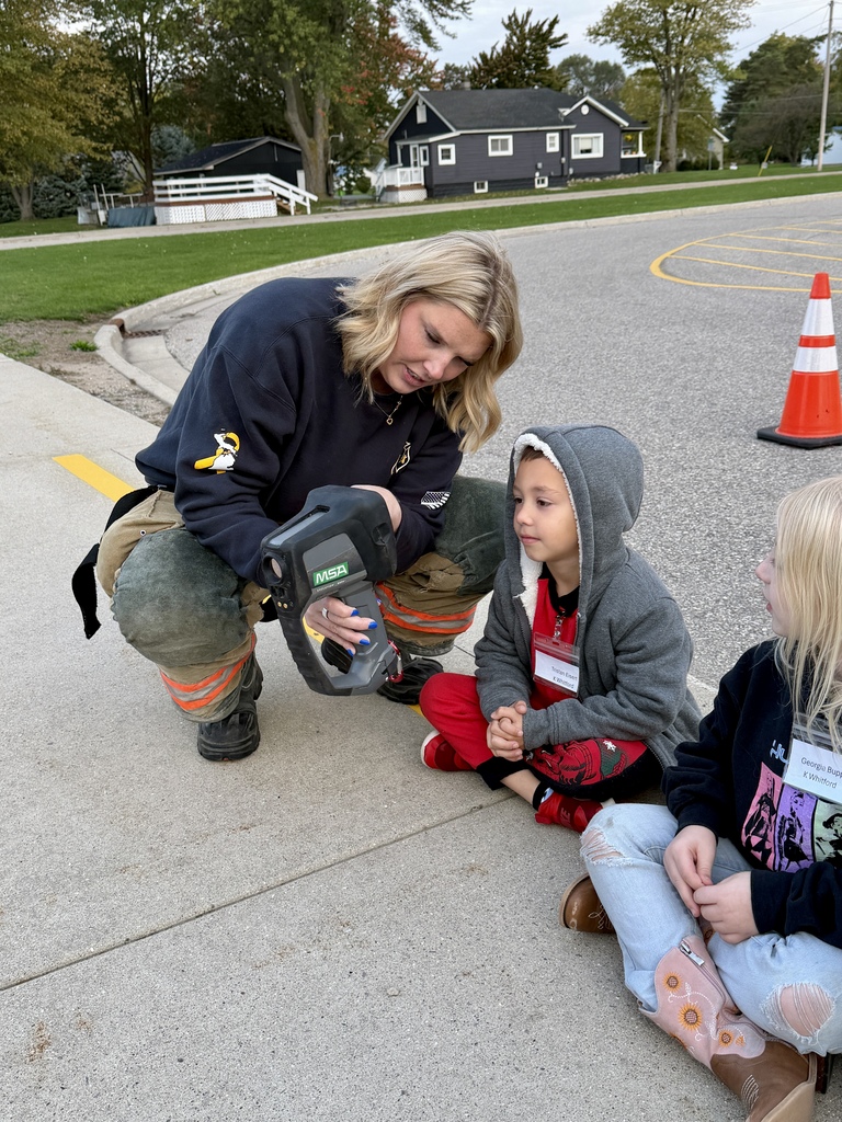 Firefighter talking to student about equipment.