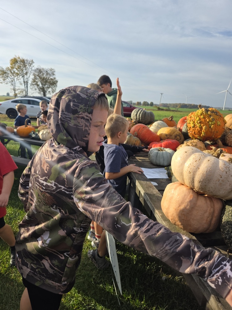 students looking at a wagon full of pumpkins.