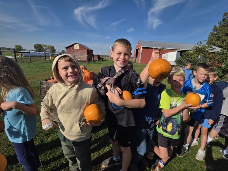 Students standing in line and holding pumpkins.