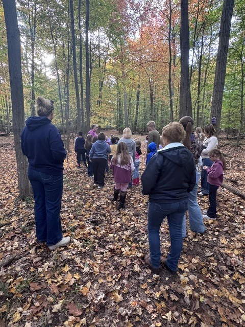 students and adults in the woods