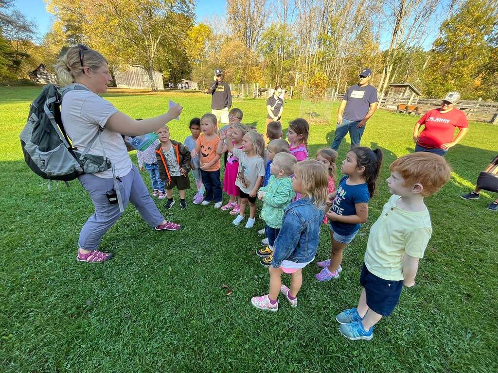 A guide teaches a group of children.