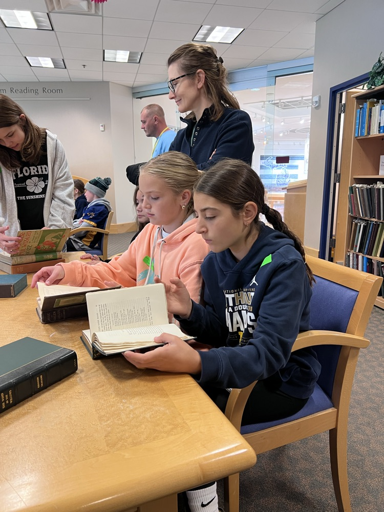 students looking at a book at the CMU library