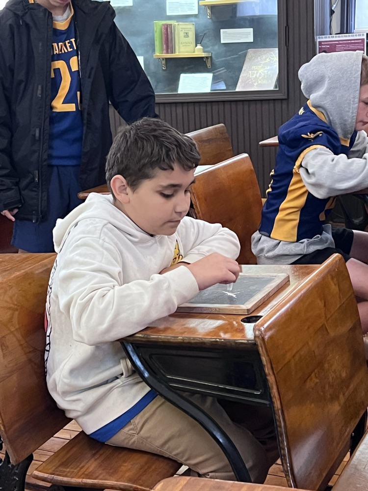 a student seated at a desk in the one room school house