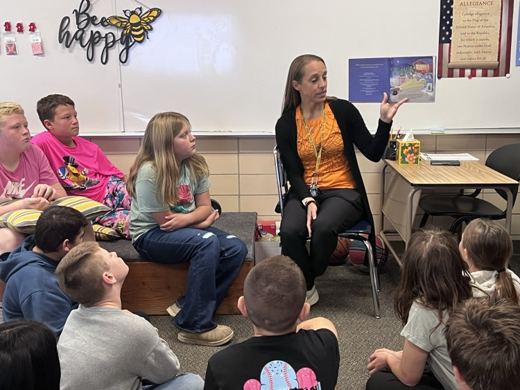students seated around Mrs. Rayburn read a Halloween story to our class 