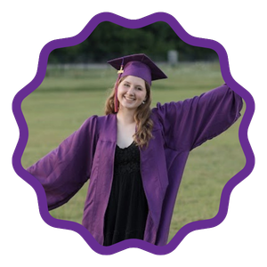 student in her graduation cap and gown smiling with her arms outstreached 