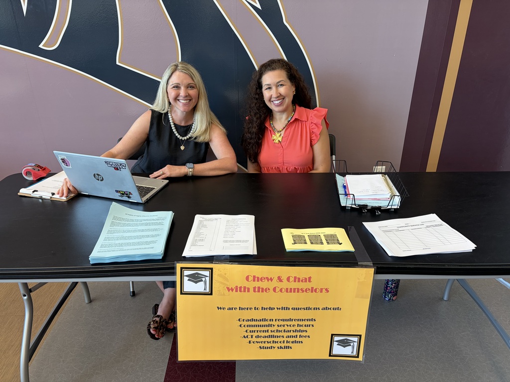 Two women sitting at a table smiling at the camera // School counselors host yearly "Chat & Chew" to remind students they are available when needed. 