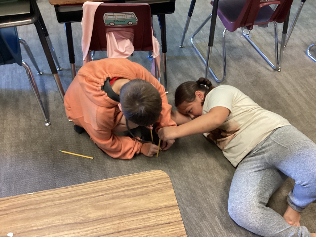 Two students are performing an experiment with marbles and rubber bands.