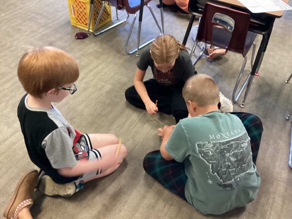 Three students sit on the floor performing an experiment with.