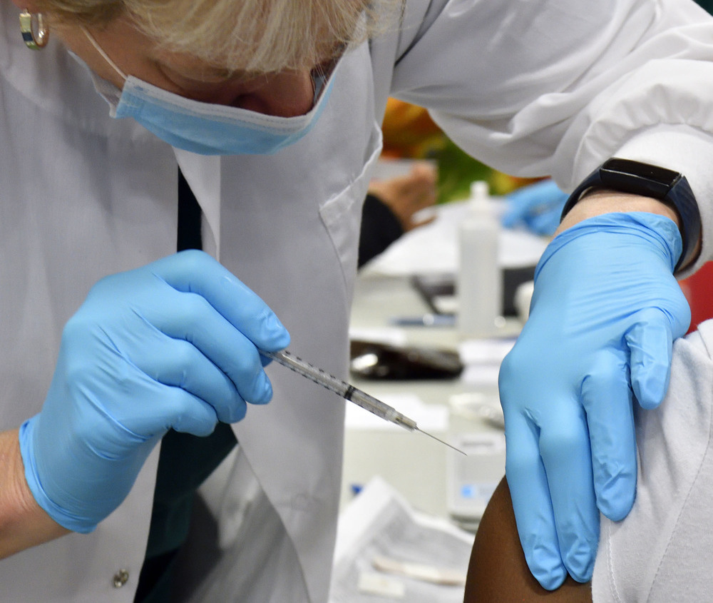 A medical professional administers a vaccination.