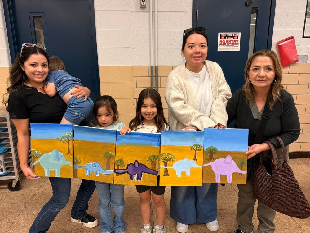 Parents and kids pose for a picture holding drawings