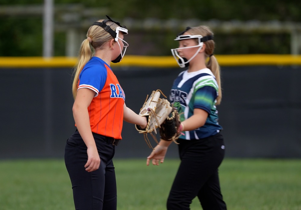 Two softball players touching gloves
