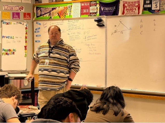 A teacher teaches at the front of the class.