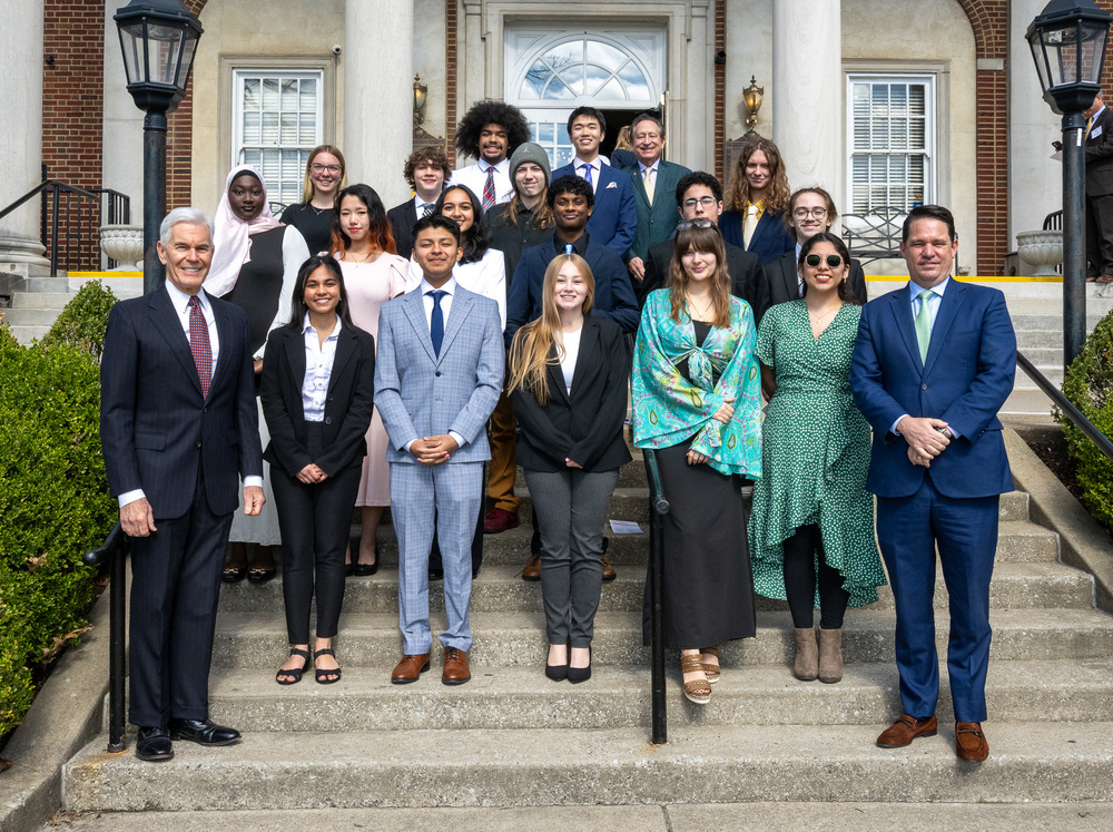 Nineteen students and three adults pose for a photo outside of the Olmsted.