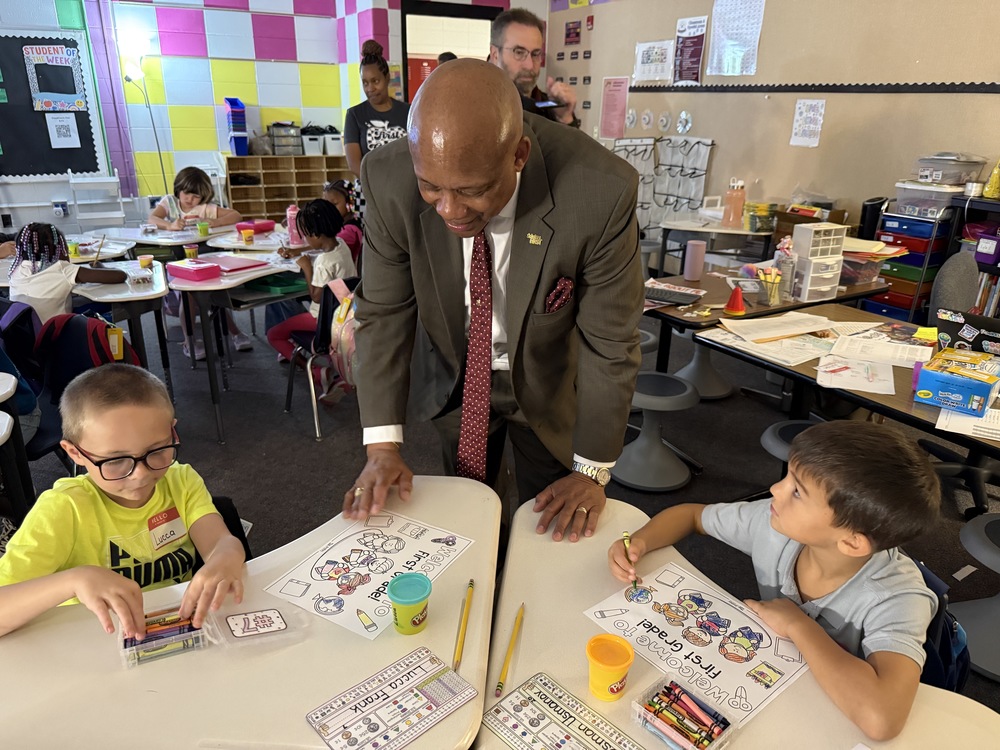 Dr. Brian Yearwood interacting with two young students. 