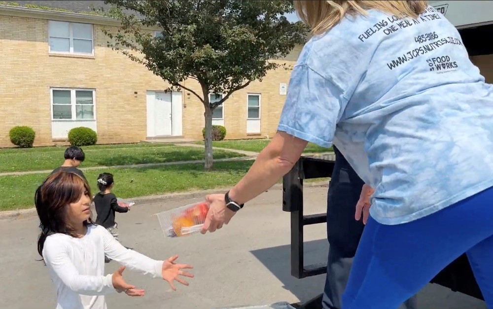 student receiving meal from school employee