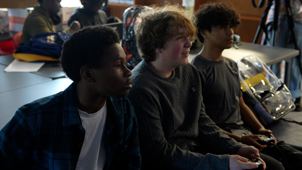 Three boys sitting looking at a tv screen playing video games