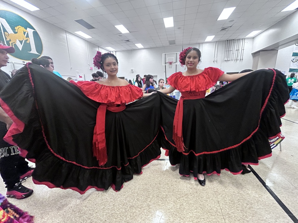Two students in cultural dresses, fanned out for the photo.