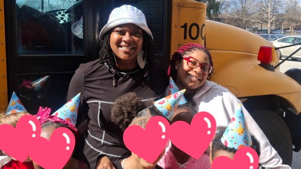 Two adults pose for a picture with five students.