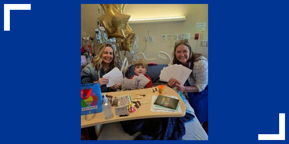 Henry Jones and two adults pose for a picture holding birthday cards and smile.