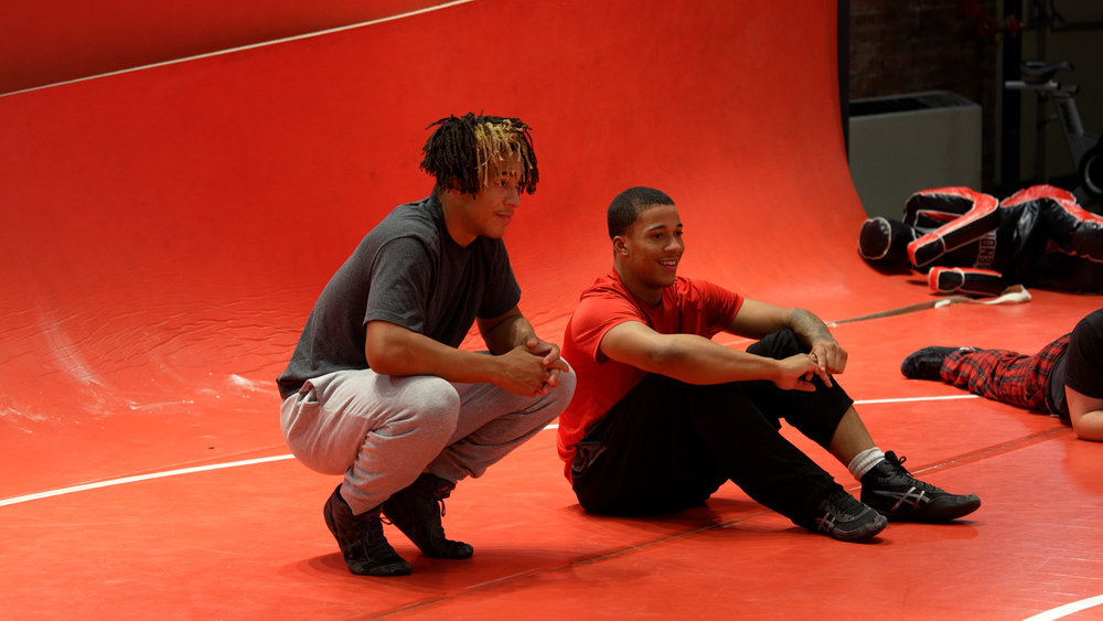 Darian and Devin Allen sitting on a wrestling mat talking to each other