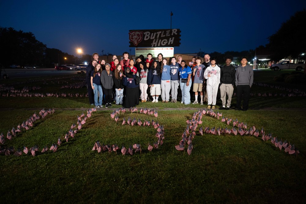 Students stand in front of American flags spelling out "USA"