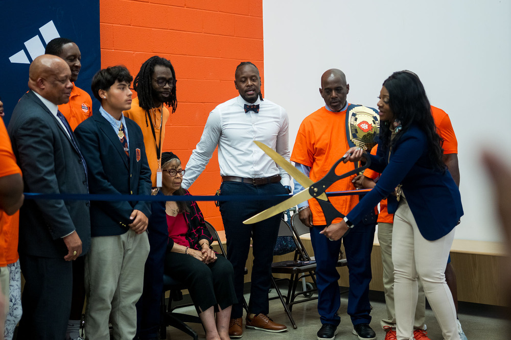 Adults and a student participate in a ribbon cutting ceremony.