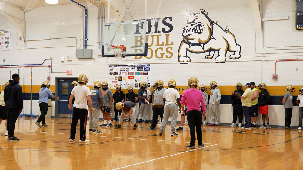 Football team practicing in a basketball gym
