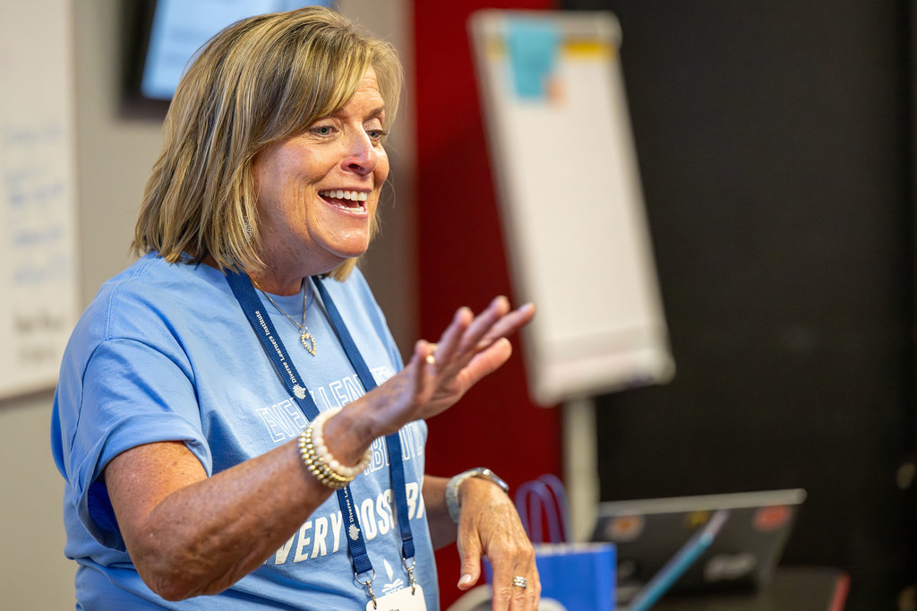 An instructor smiles and raises her hand.