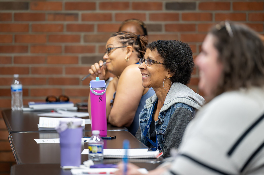 Participants sit at a table and smile.