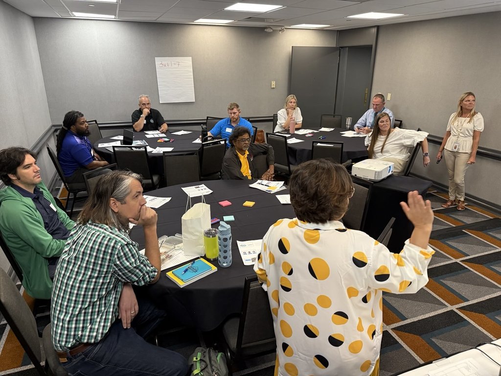 Educators sit around tables during a conference.