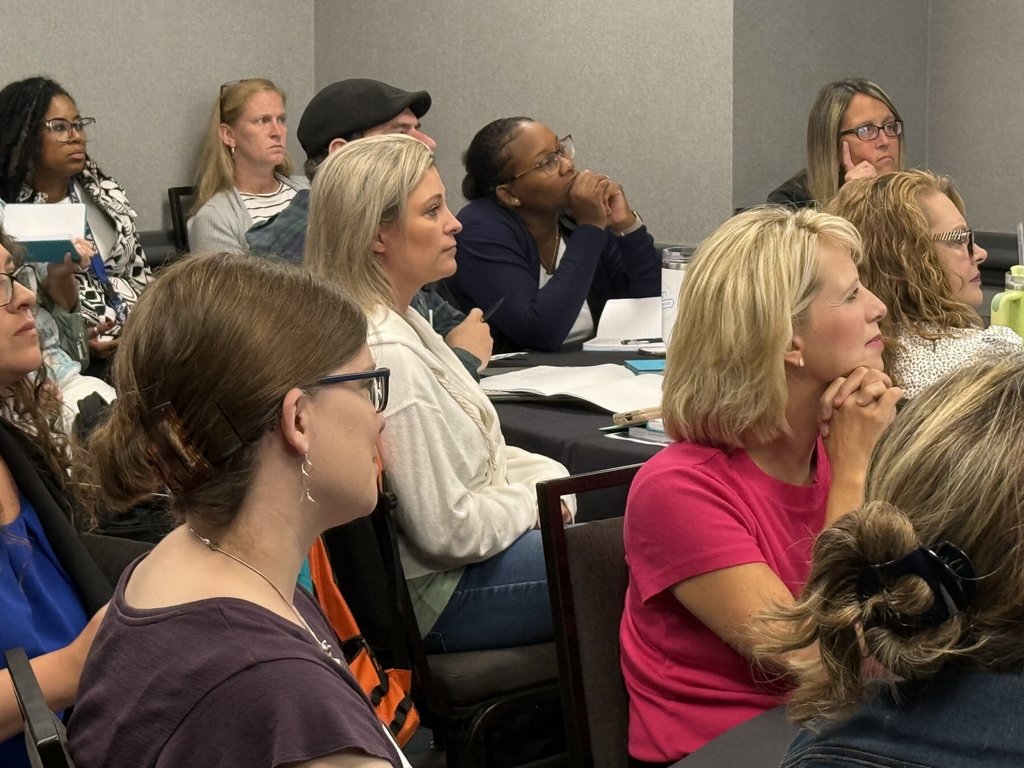 Educators sit around tables during a conference.