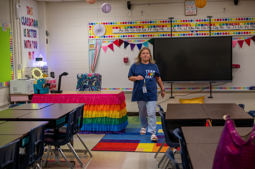 A teacher walks in her brightly decorated classroom. 