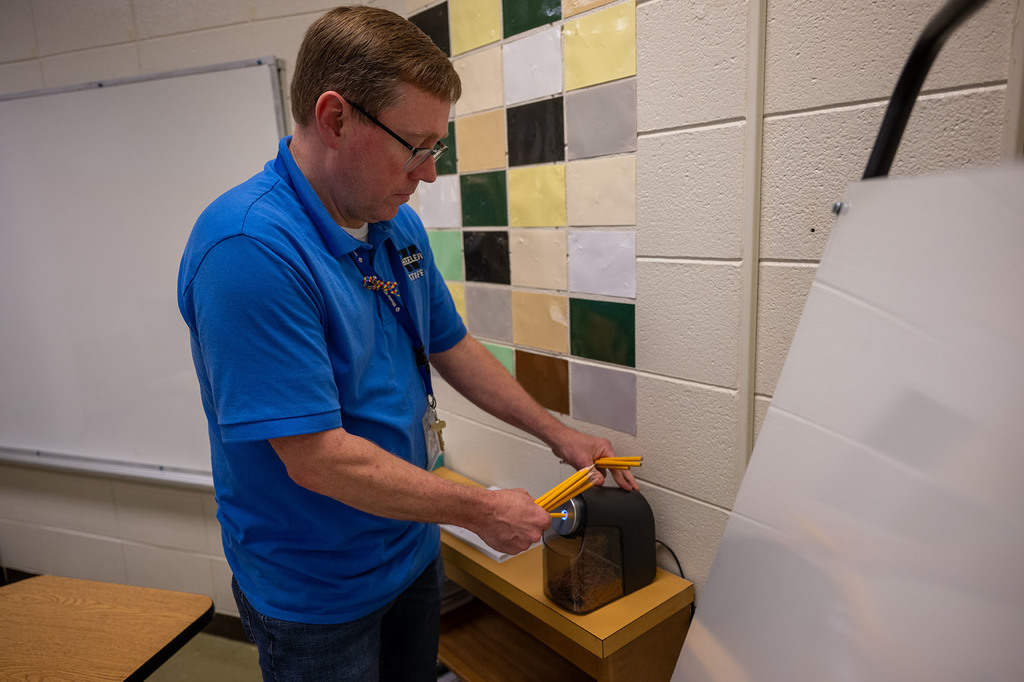 A teacher sharpens pencils in his classroom.